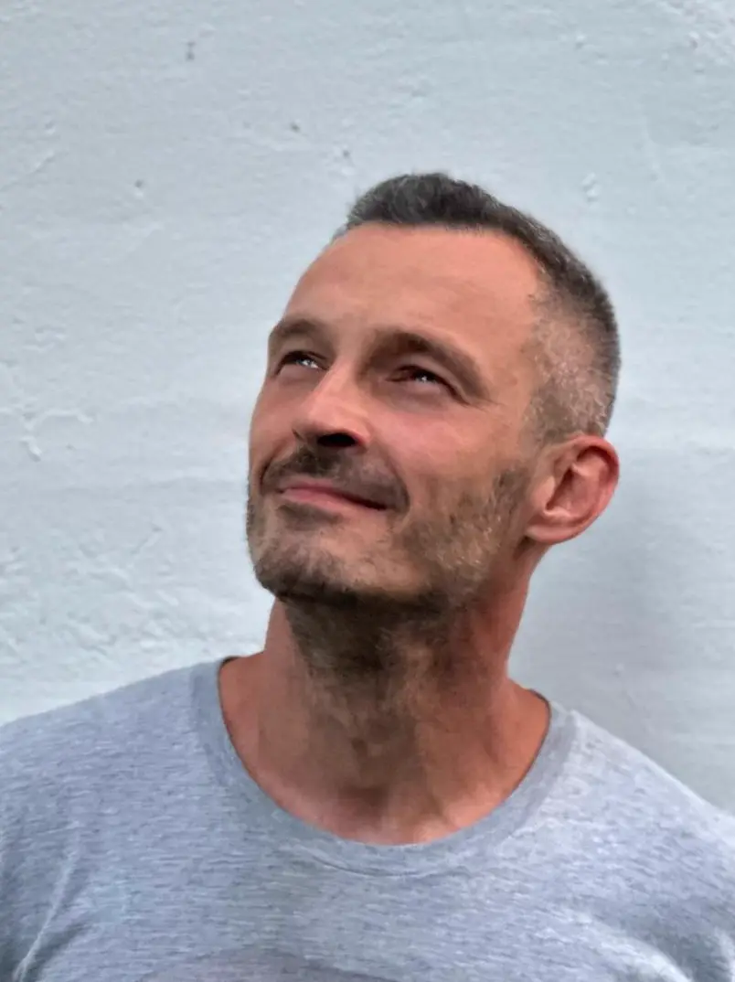 A portrait of Andrei, standing, in a navy T-shirt, outside – no pretense, exactly as he is.